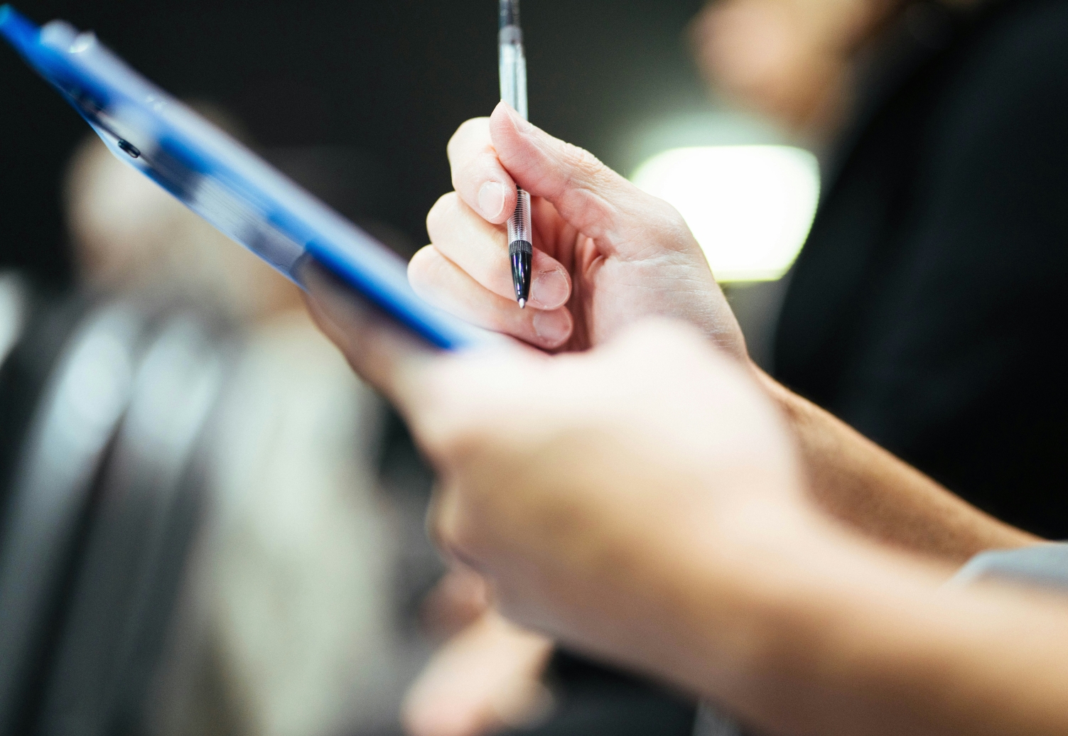 Person writing on clipboard with pen