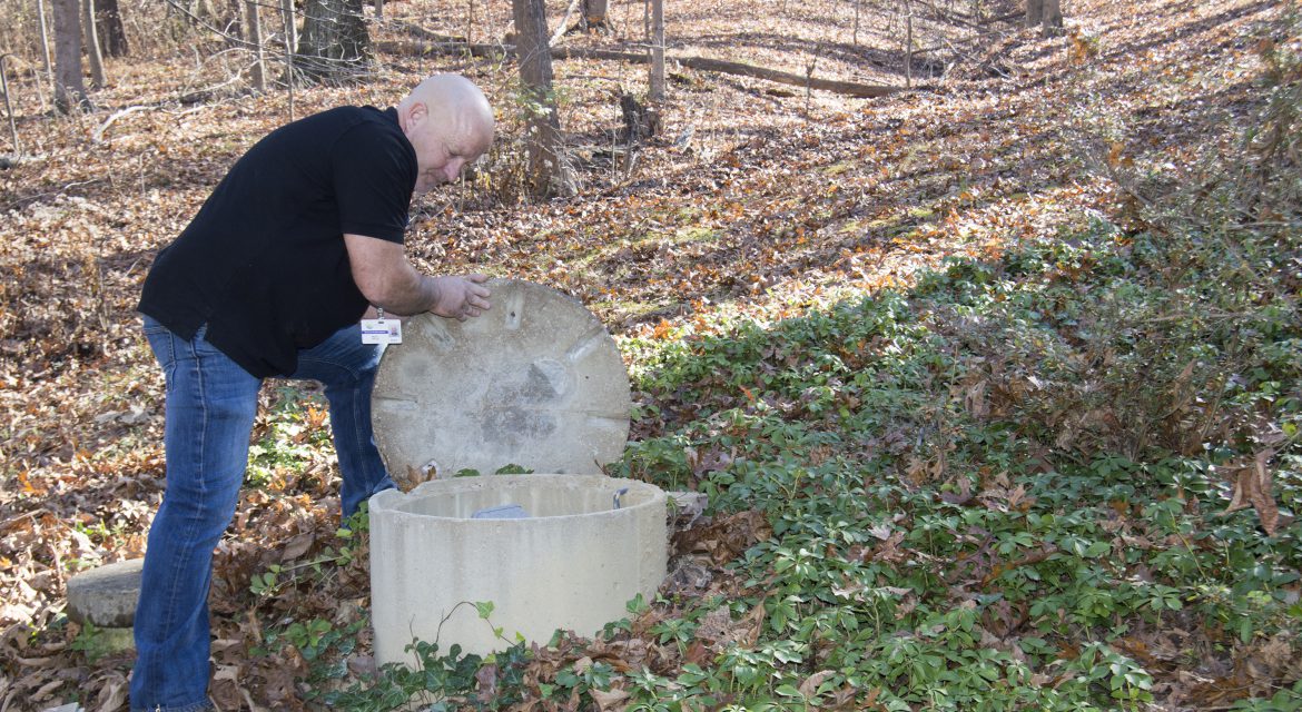 Health inspector lifting lid of septic tank for inspection